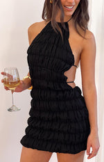 Side view of a black ruched mini dress with a halter neck and cutouts secured by thin straps