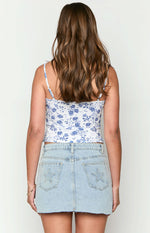 Rear view of a white singlet with blue floral print and thin adjustable spaghetti straps