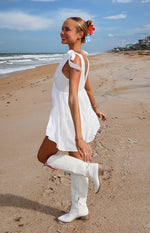 Side view of a white mini dress with tie-shoulder straps, a deep scoop back, and a tiered flowy skirt