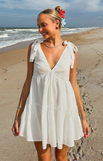 White mini dress with a deep V-neckline, tie-shoulder straps, and a tiered skirt design