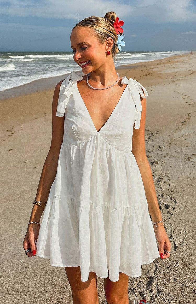 White mini dress with a deep V-neckline, tie-shoulder straps, and a tiered skirt design