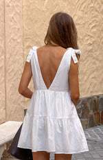 Rear view of a white mini dress with a deep V-back, tie-shoulder straps, and a tiered skirt