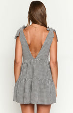 Rear view of a black gingham mini dress showing the deep V-back, tie-shoulder straps, and tiered skirt