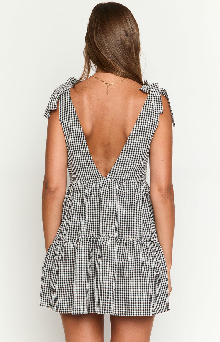 Rear view of a black gingham mini dress showing the deep V-back, tie-shoulder straps, and tiered skirt