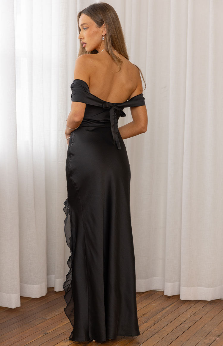 Rear view of a black off-shoulder maxi dress with a tie-back detail and side ruffle trim