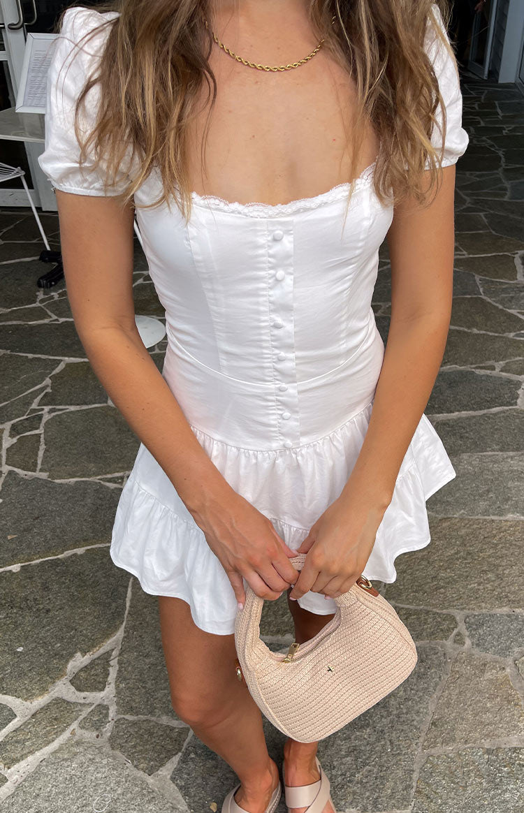 Front view of a white mini dress with a square neckline, lace trim, button-front bodice, and ruffled hem