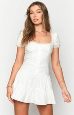 White mini dress with a lace-trimmed square neckline, short puff sleeves, and button-front bodice