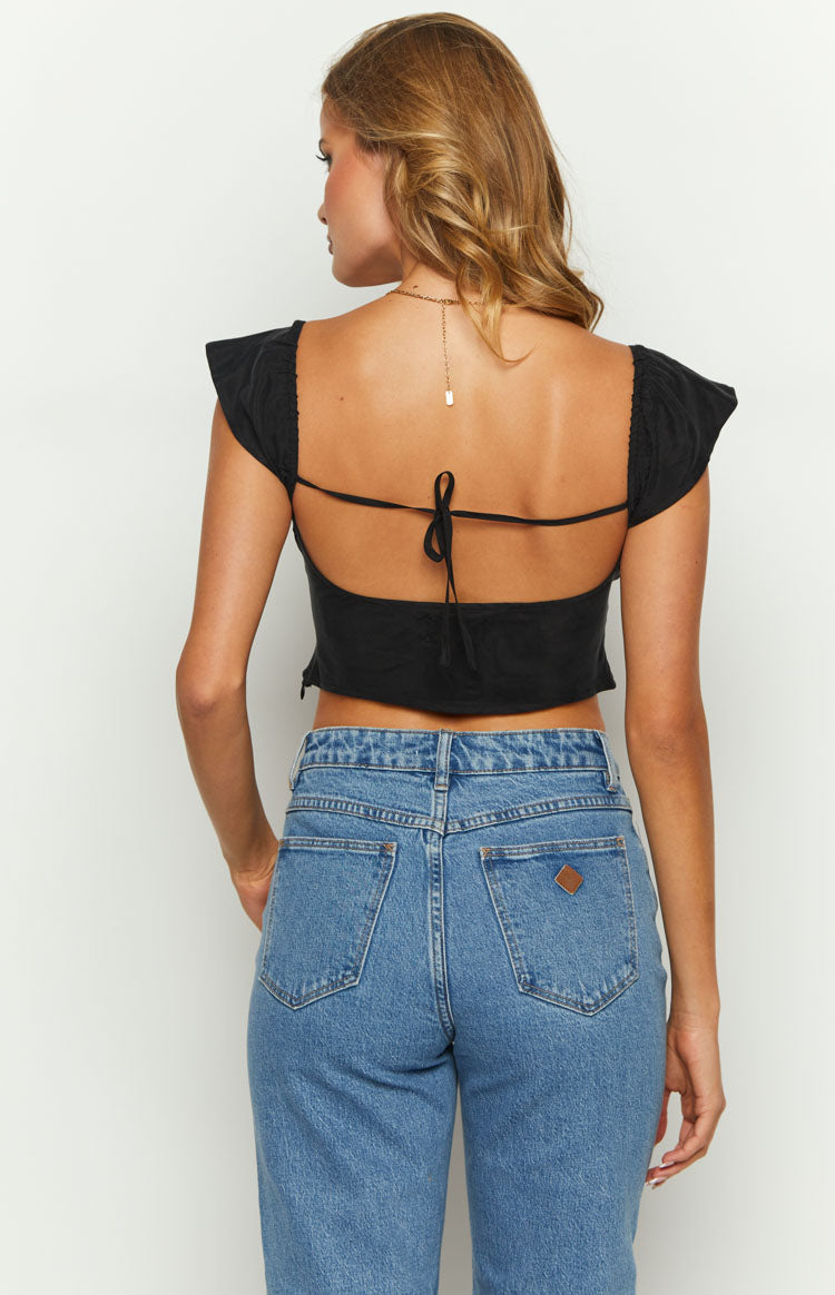Rear view of a black crop top with an open back, tie closure, and short ruffled sleeves