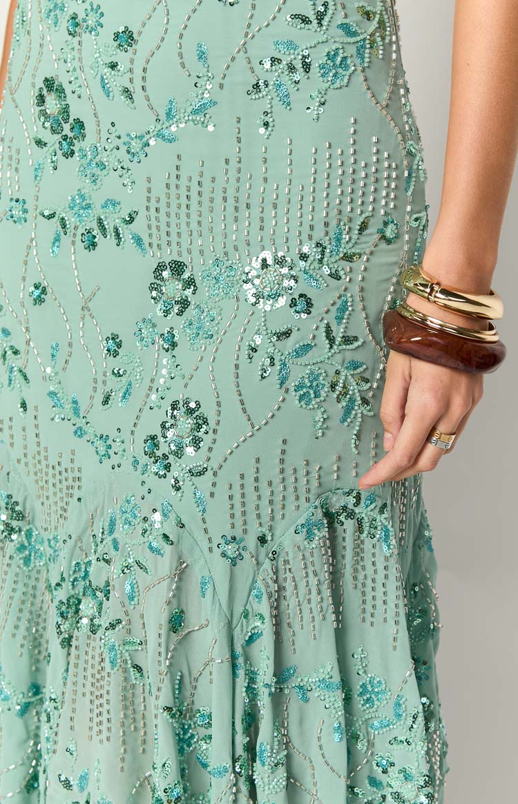 Close-up of the mint green sequin midi dress showing intricate teal floral embroidery, silver beading, and flared hem