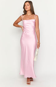 Front view of a pink satin maxi dress with a square neckline, tie-up spaghetti straps, and a ruched side