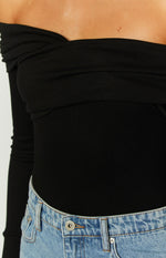 Close-up of the black ribbed off-shoulder bodysuit showing the twisted bust detail and long sleeve
