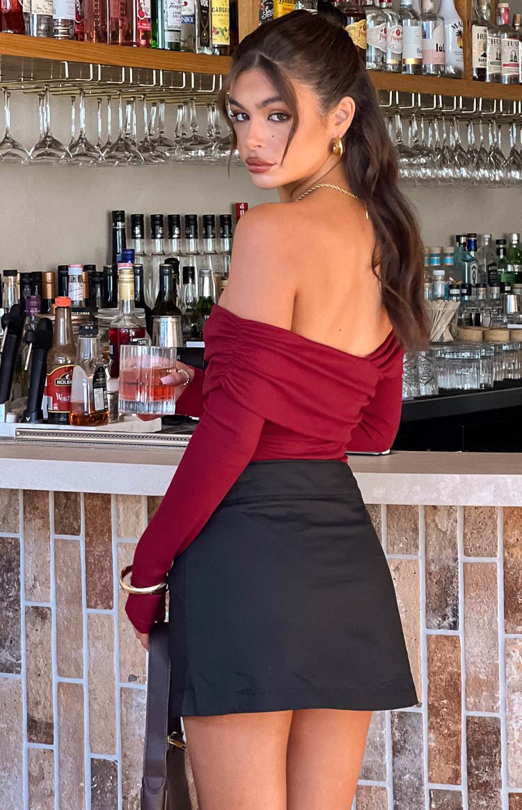 Rear view of a red off-shoulder bodysuit with long sleeves and ruched detailing