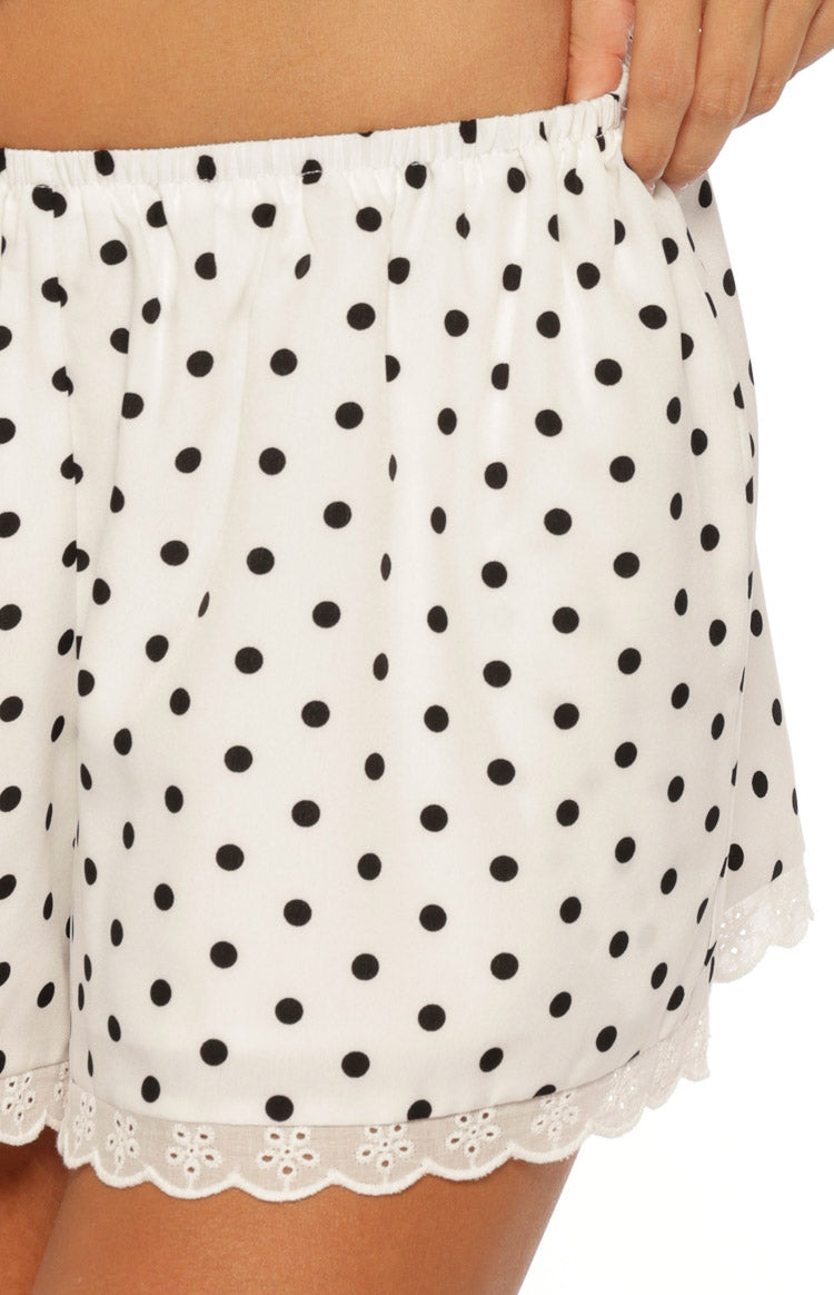Close-up of the white polka dot shorts showing the elasticated waist and scalloped broderie anglaise hem