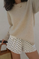 Close-up of the relaxed fit white polka dot shorts with a scalloped broderie anglaise hem