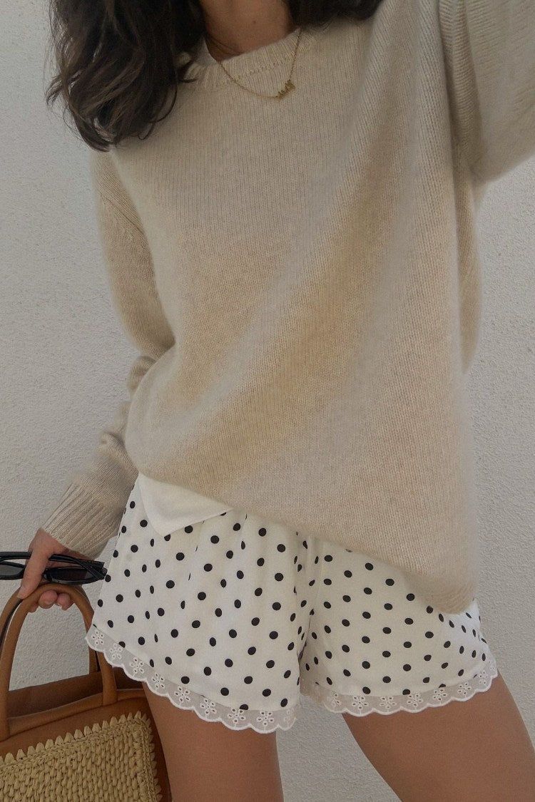 Close-up of the relaxed fit white polka dot shorts with a scalloped broderie anglaise hem