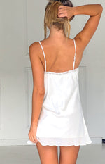 Rear view of a cream satin mini dress with thin adjustable straps, lace trim, and a ruffled hem