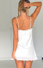 Rear view of a cream satin mini dress with thin adjustable straps, lace trim, and a ruffled hem