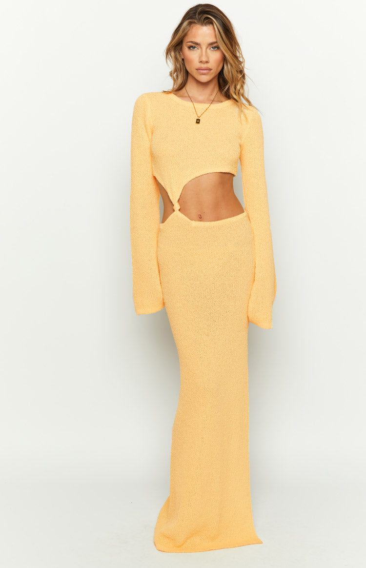 Yellow knit maxi dress with long sleeves and prominent side cutouts at the waist