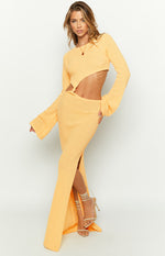 Yellow long sleeve knit maxi dress with an asymmetrical waist cutout and a high leg slit