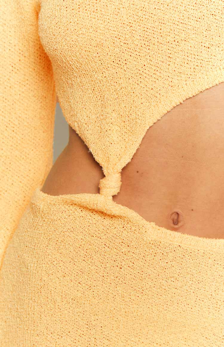 Close-up of the side cutout detail on a yellow long sleeve knit maxi dress