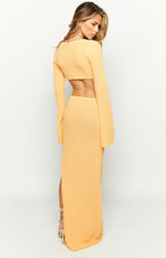 Rear view of a yellow textured knit maxi dress with an open back, cropped top, long flared sleeves, and a side slit