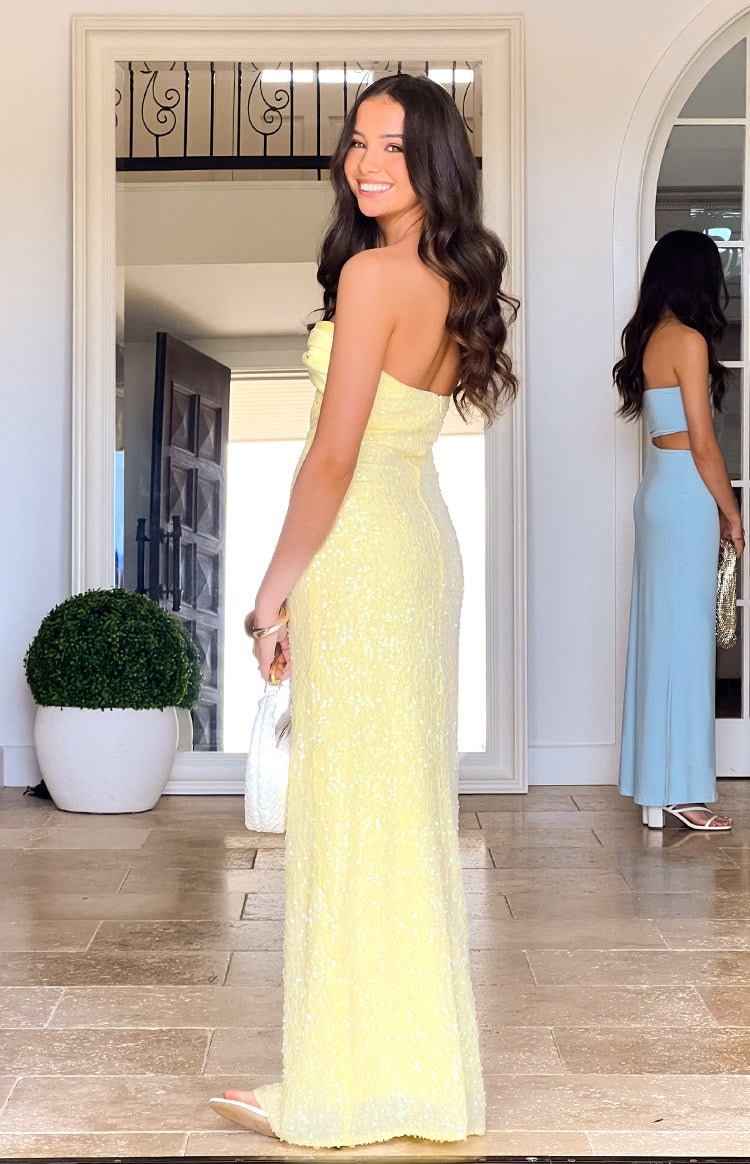 Side view of a yellow sequin strapless maxi dress showing the fitted bodice and flowing skirt