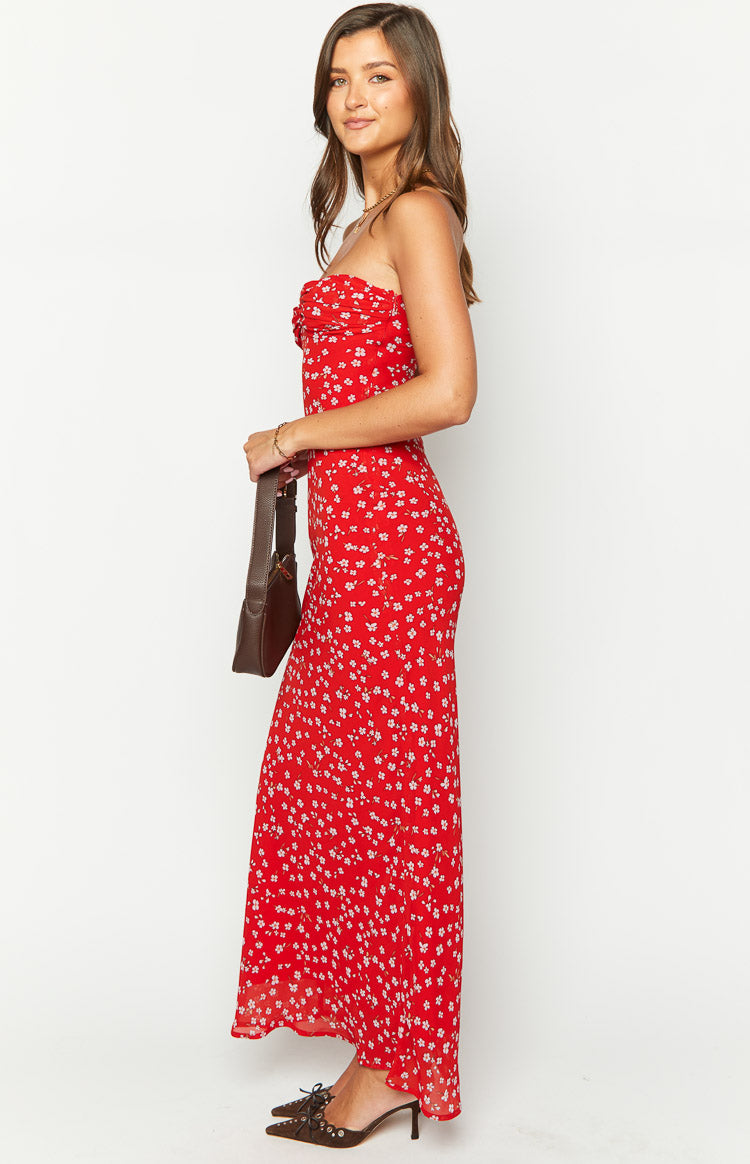 Side view of a red floral strapless maxi dress with a ruched bust and flowing skirt