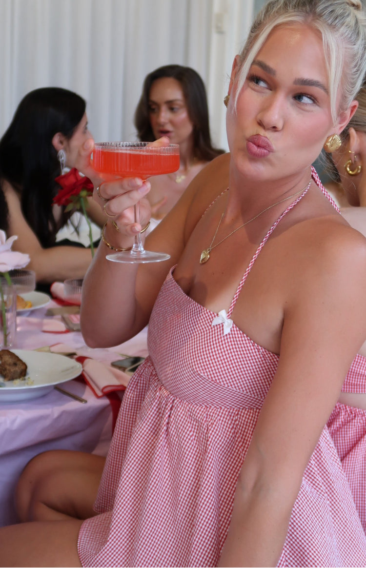 Close-up of the red gingham halter top with a small white bow detail and gathered hem