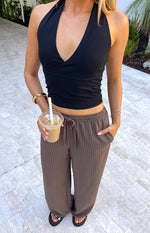 Close-up of the brown wide-leg pants with a tied drawstring waistband and subtle vertical stripe texture