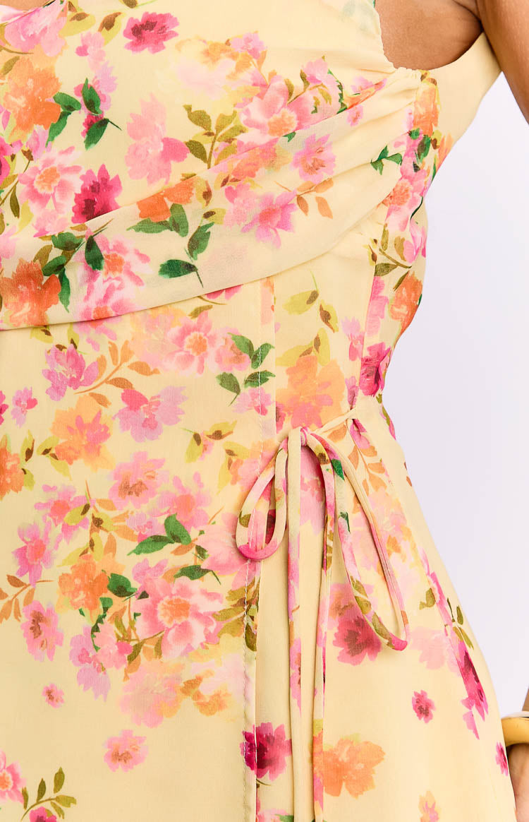 Close-up of the yellow floral mini dress showing the side tie detail and draped bodice