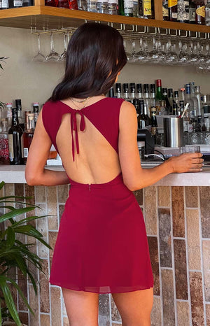 Rear view of a red chiffon mini dress with a back tie closure and large triangular cutout