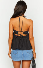 Rear view of a black halter top with a tie-neck, open back, and a gathered tie-back closure above a flared peplum hem