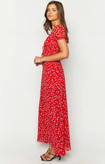 Side view of a red floral maxi dress with short sleeves, ruched bust with tie details, and a flowy skirt