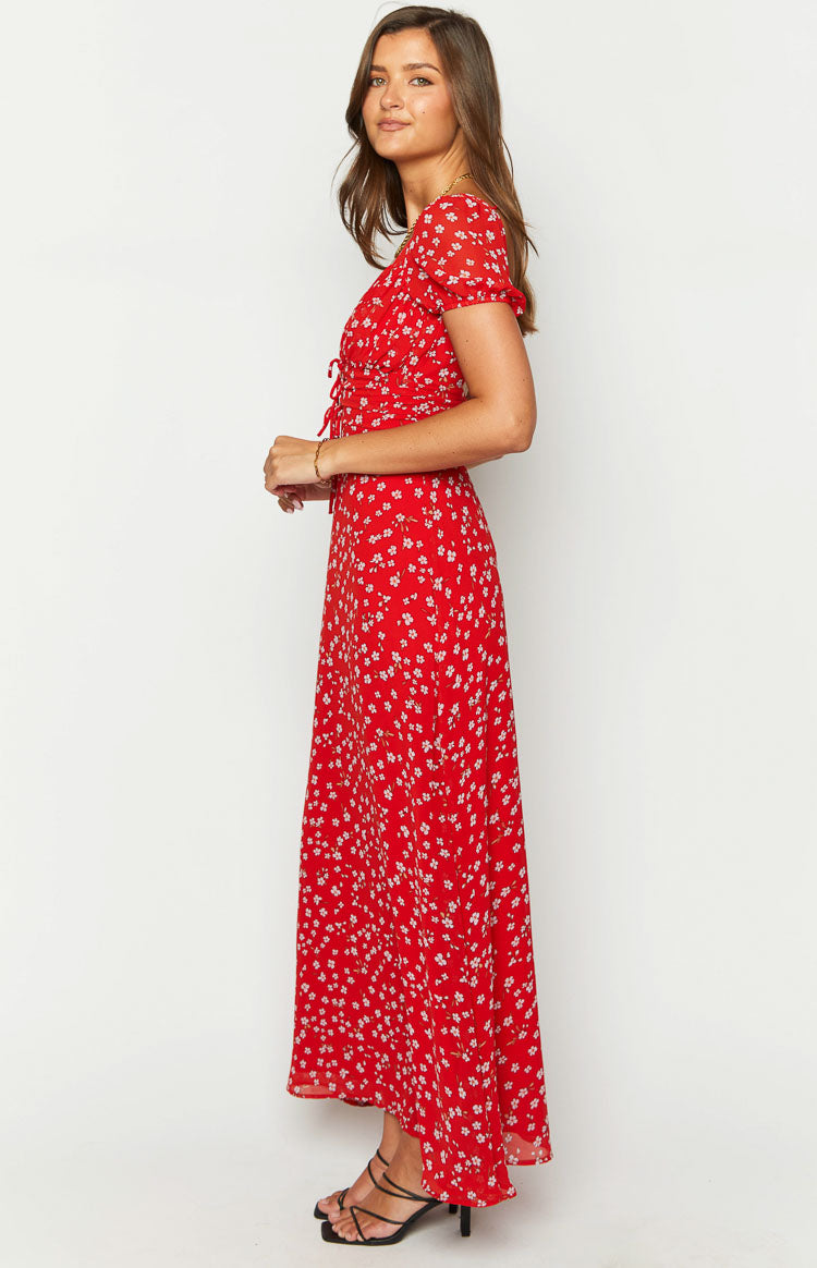 Side view of a red floral maxi dress with short sleeves, ruched bust with tie details, and a flowy skirt