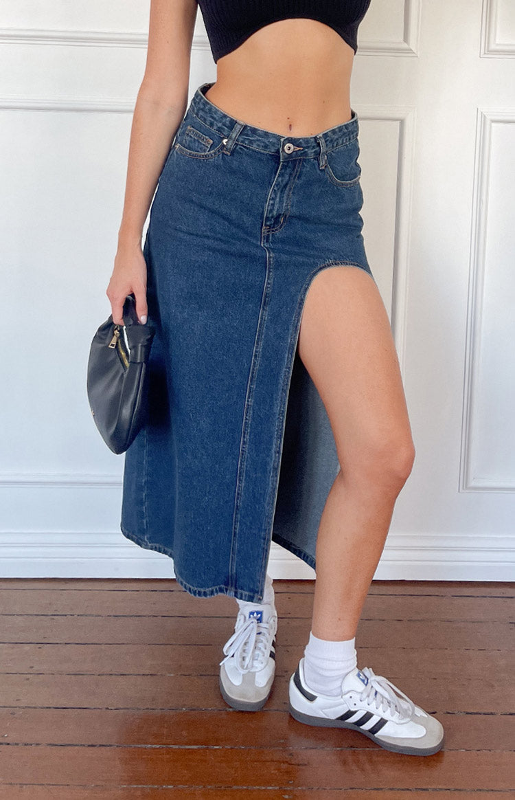 Close-up of the dark wash denim midi skirt showing the front button, pocket, and large side cutout