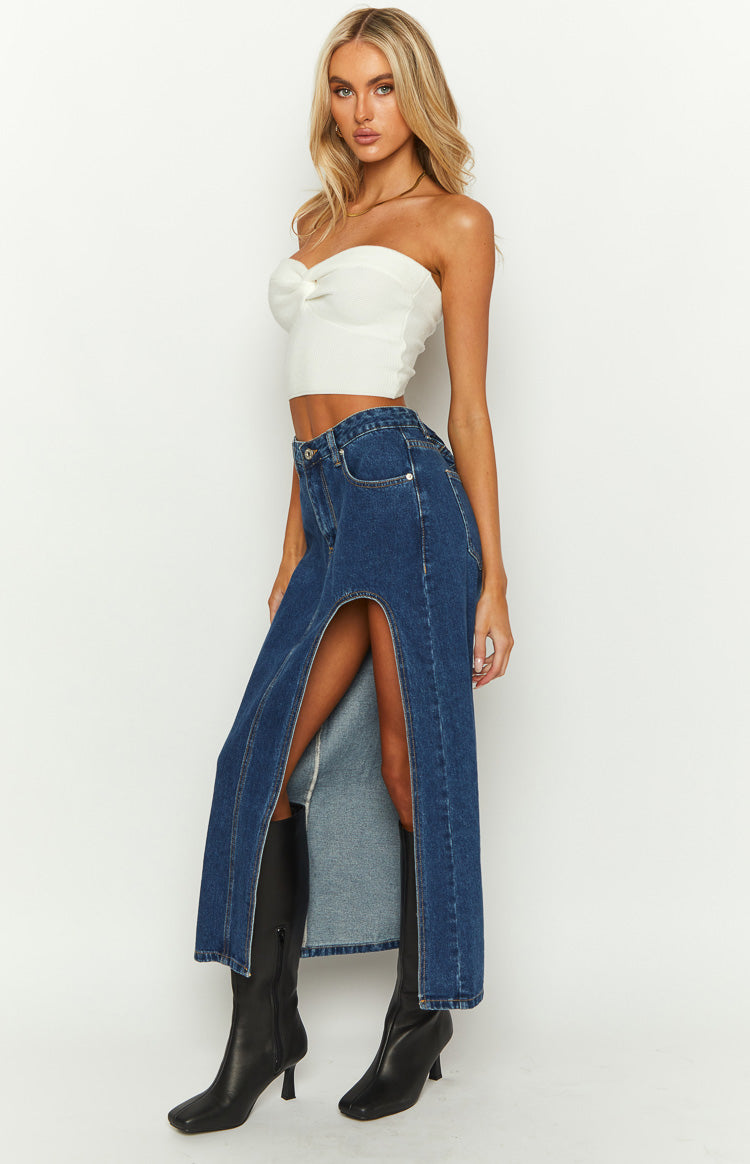 Side view of a dark wash denim midi skirt with a high split up the left side