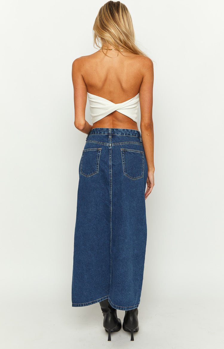 Full length view of the dark wash denim midi skirt with a high left leg slit and asymmetrical hem