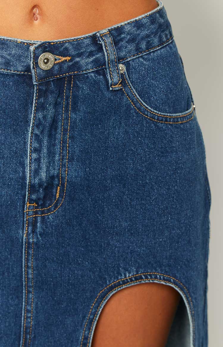 Side view of a dark wash denim midi skirt with a high left side split and a relaxed A-line silhouette