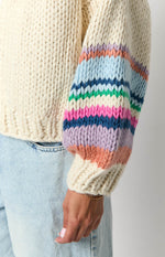 Close-up of the cream chunky knit cardigan sleeve with multi-coloured horizontal stripes and a ribbed cuff