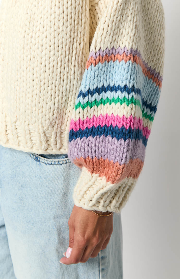 Close-up of the cream chunky knit cardigan sleeve with multi-coloured horizontal stripes and a ribbed cuff