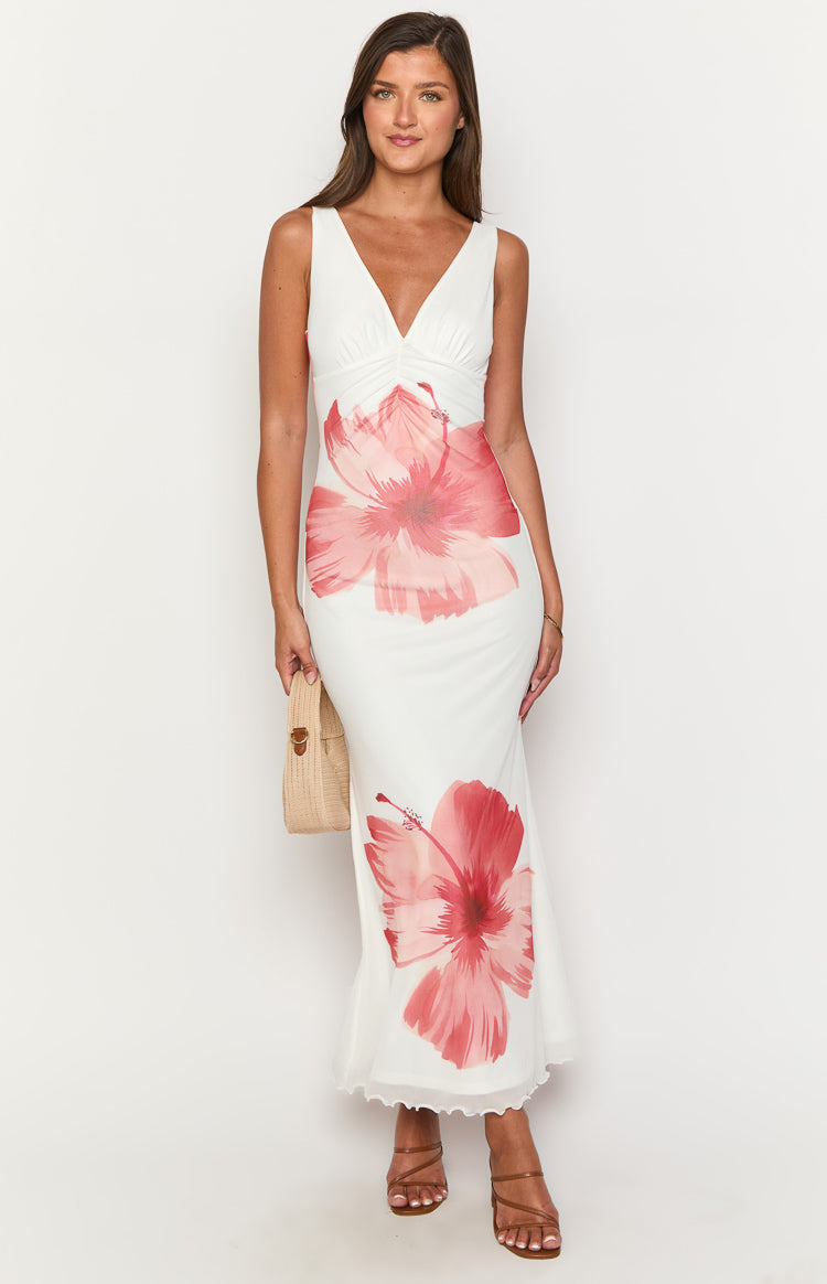 White sleeveless maxi dress with a V-neck, ruched bust, large pink hibiscus prints, and ruffled hem