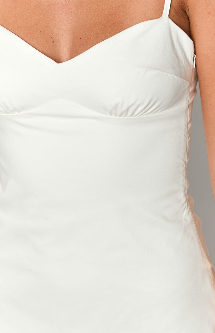 Close-up of the white mini dress showing the sweetheart neckline, gathered underbust, and side zipper