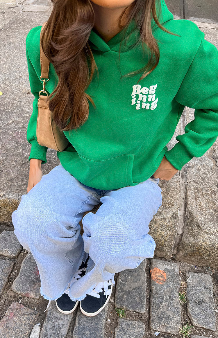 High-angle view of a bright green hoodie with a white 'Beginning' logo and a large front kangaroo pocket