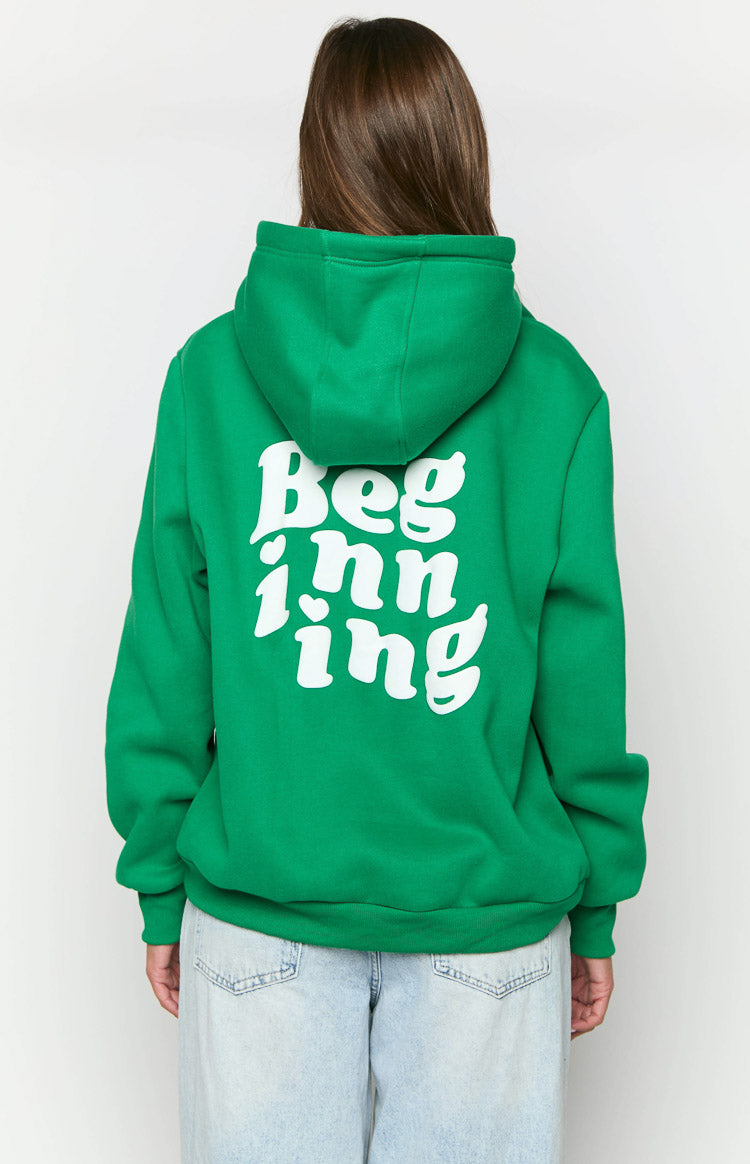 Rear view of a green oversized hoodie with a white 'Beginning' graphic print on the back, featuring small heart details