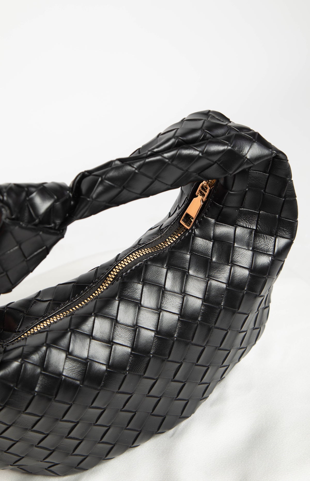 Close-up of the black woven PU shoulder bag showing the gold-toned zipper and textured material