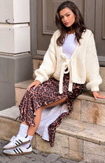 Rear view of a cream chunky knit cardigan with a deep V-back and waist tie detail