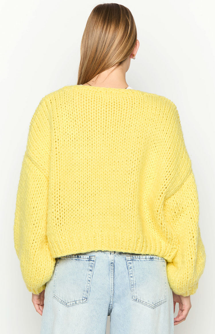 Rear view of a yellow chunky knit cardigan with a relaxed fit and voluminous long sleeves
