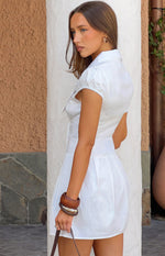 Side view of a white mini dress with a scalloped lace collar, puffed sleeves, and a pleated skirt
