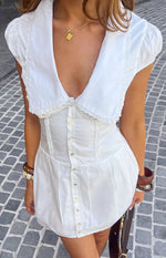 White collared mini dress with deep V-neck, lace trim, puffed sleeves, button front, and corset bodice