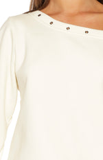 Close-up of the cream sweater's asymmetric neckline with a row of silver eyelets